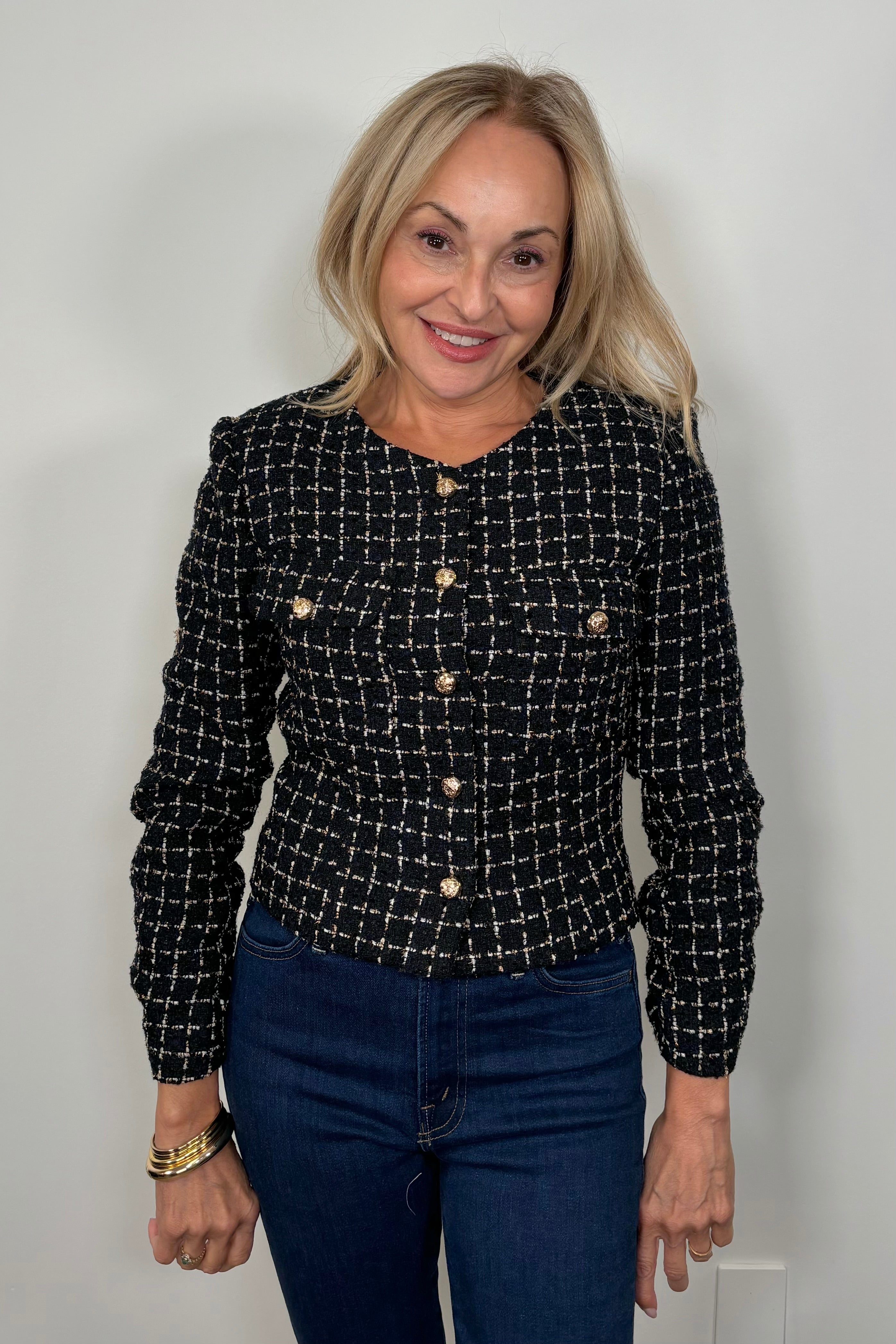 Front view of a woman wearing a navy houndstood patterned blazer with gold hardware
