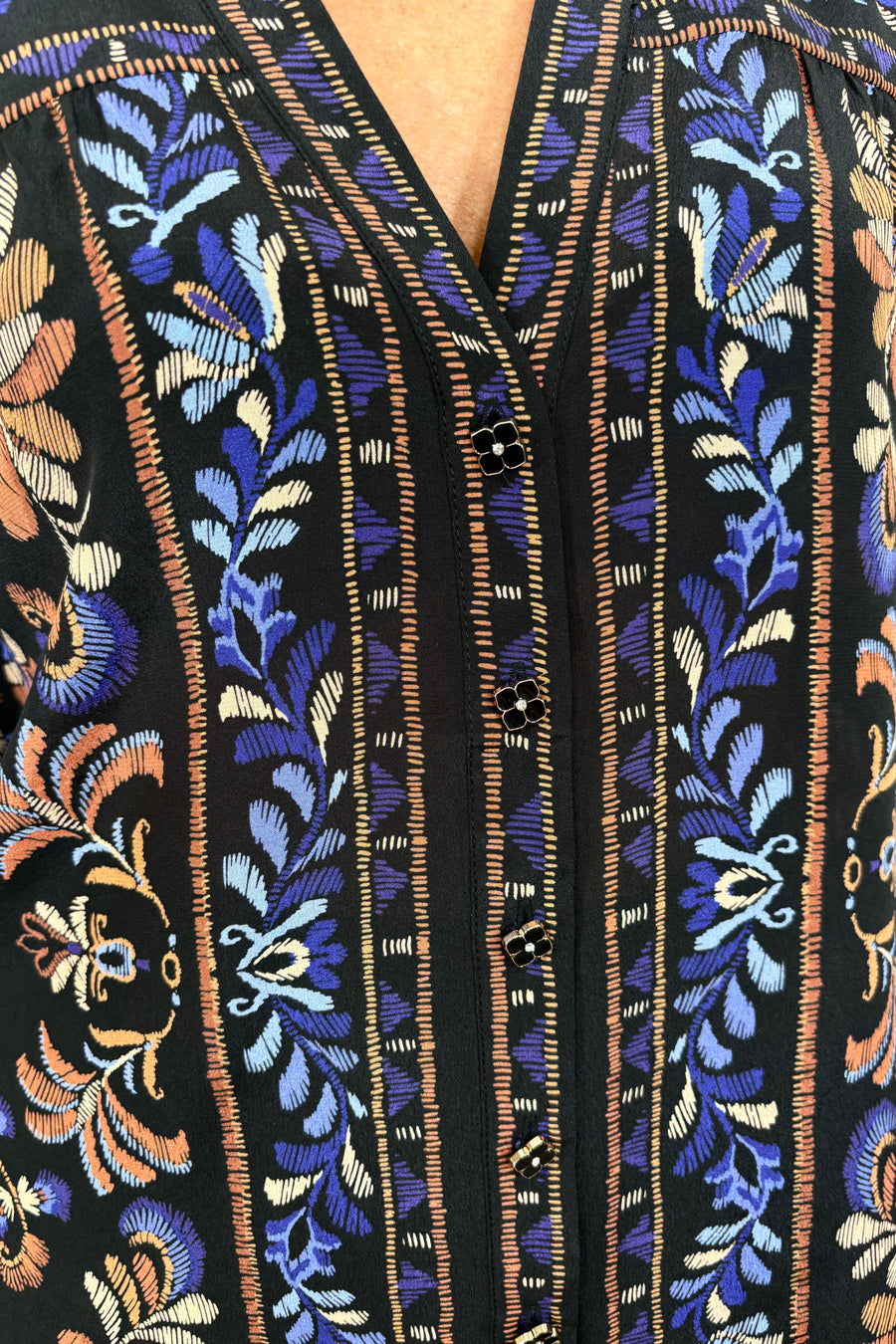 close up of woman wearing a v-neck black silk printed long sleeve blouse