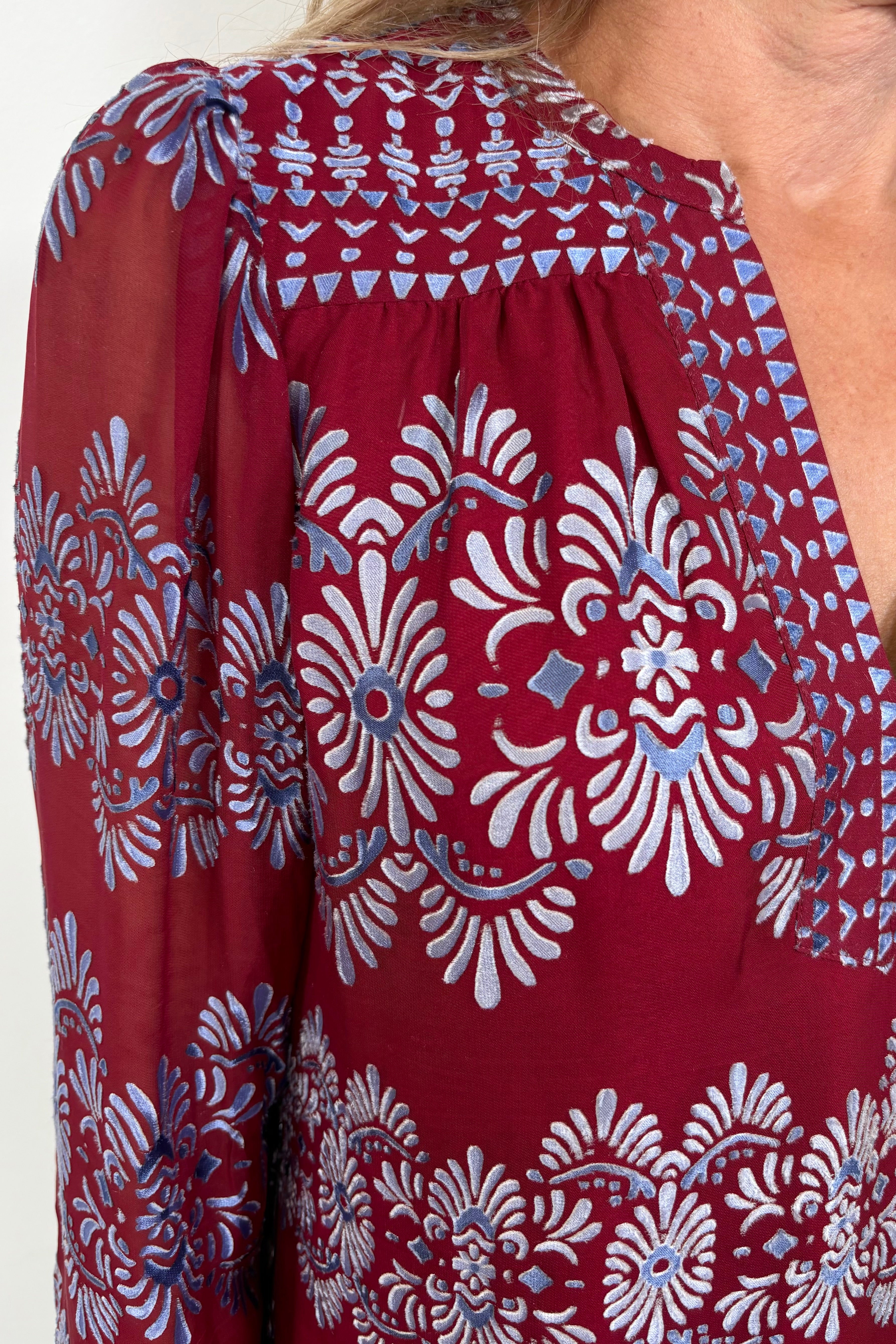 Close-up of the neck line wearing a silk mix burnout red long sleeve blouse