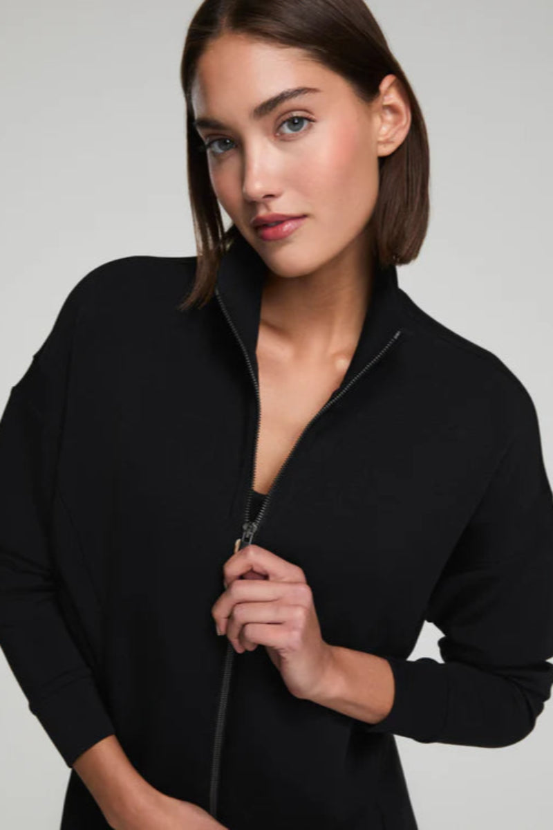 Woman wearing a black jacket against a plain background