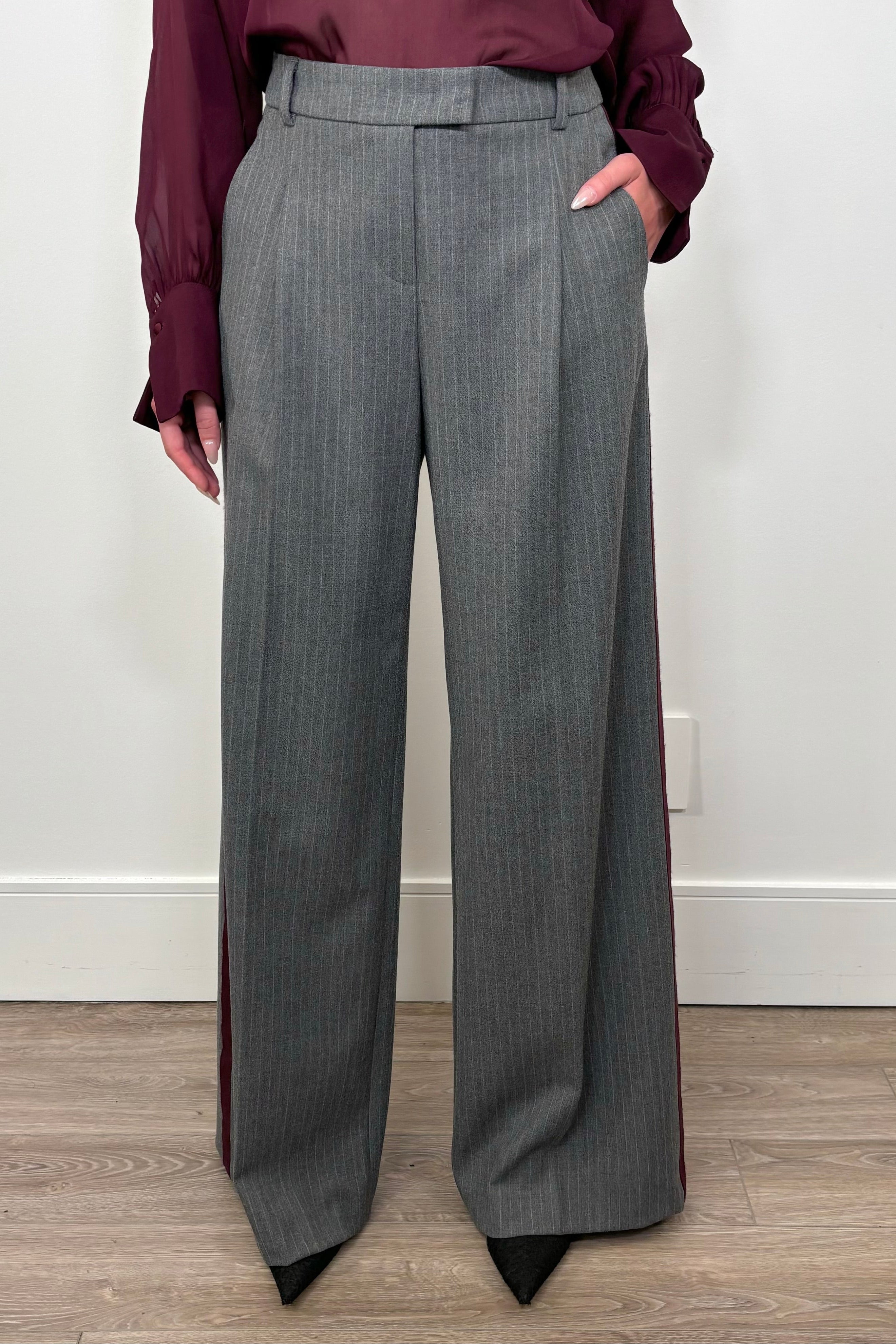 Front view of woman wearing a gray pinstripe wide leg pant with a burgundy line down the leg