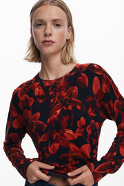Person wearing a red and black floral patterned sweater on a white background