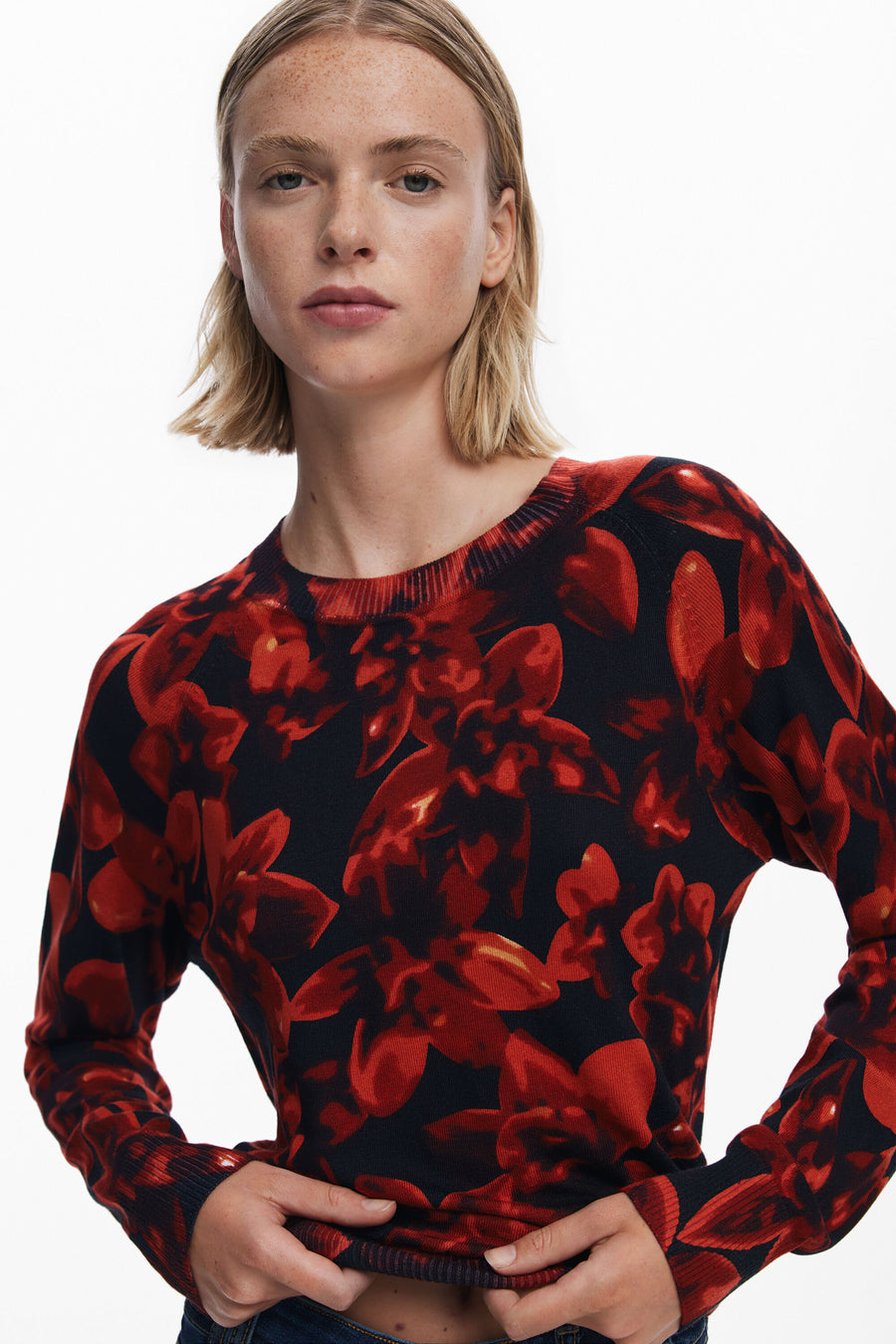 Person wearing a red and black floral patterned sweater on a white background