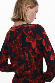 Person wearing a red and black floral patterned top on a white background