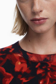 Close-up of woman wearing a red and black floral sweater on a white background