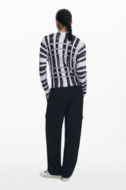 Back  view of woman wearing a light-weight plaid black, white and lilac sweater