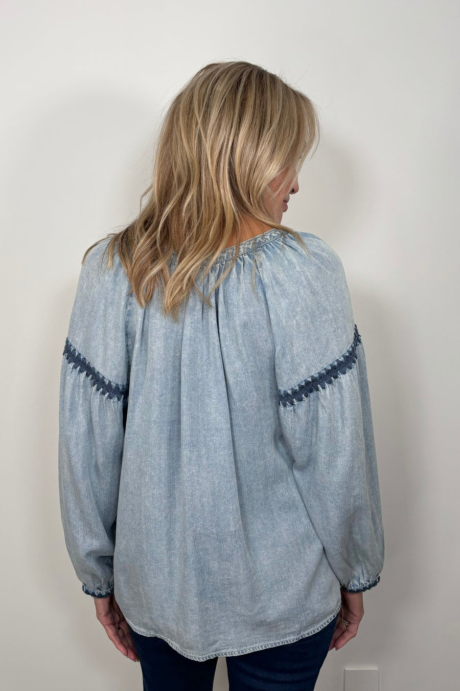 Back view of woman wearing a blue tencel blouse with stitch detailing