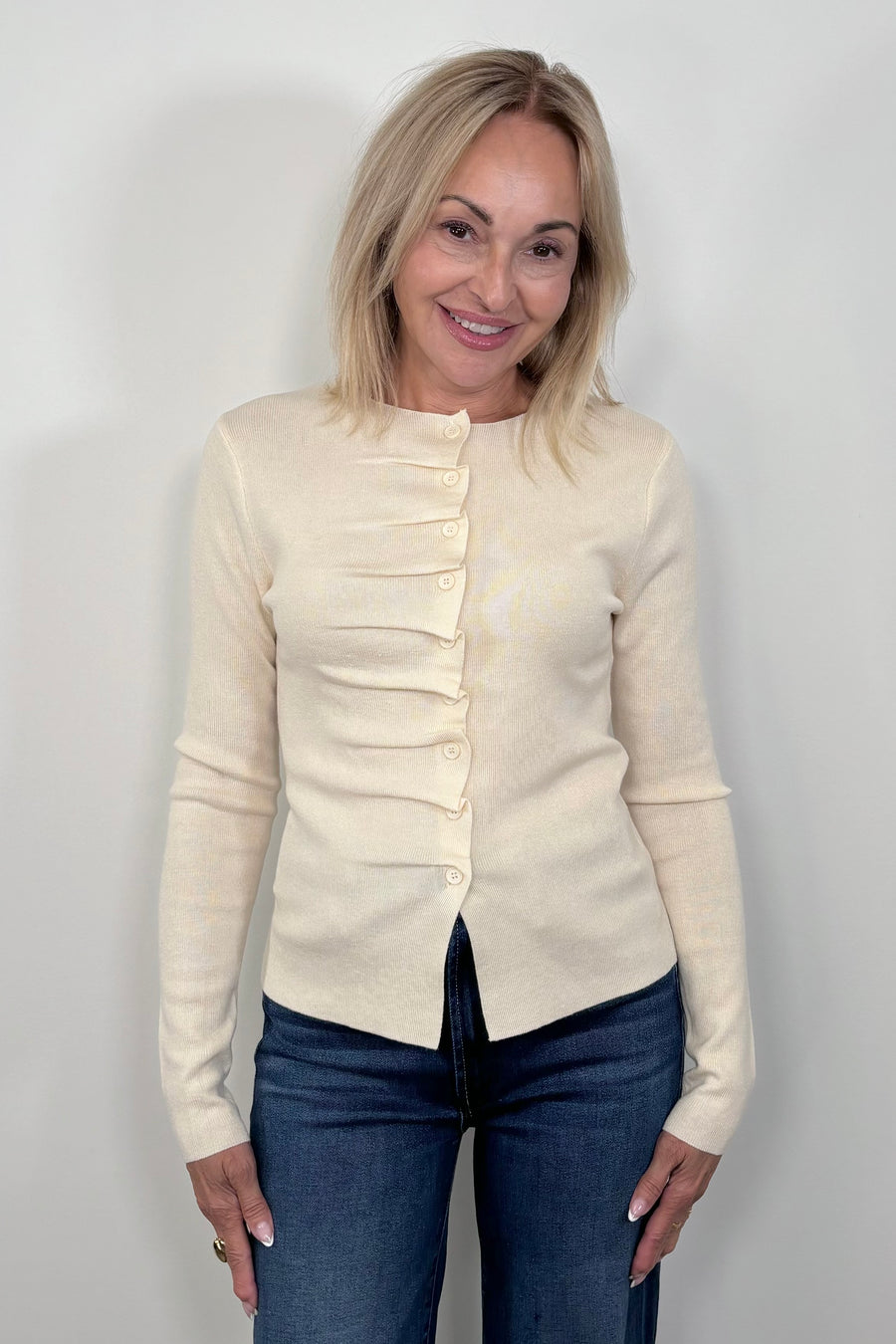 Front view of woman wearing a rouched in the buttons cream long sleeve knitted top