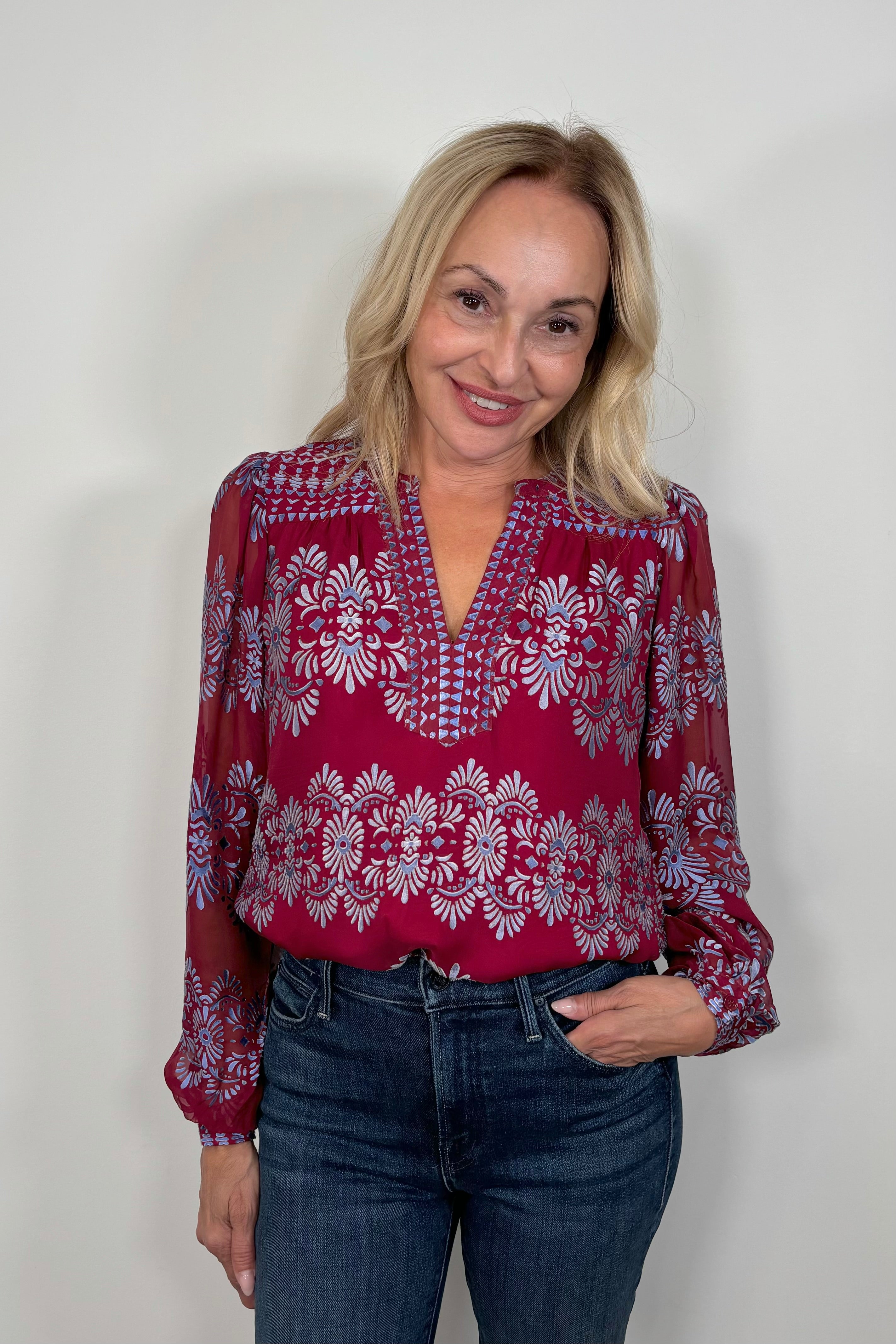 Front view of woman wearing a silk mix red long sleeve burnout blouse tucked in