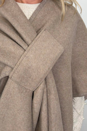 woman wearing a beige cape that looks like a bow