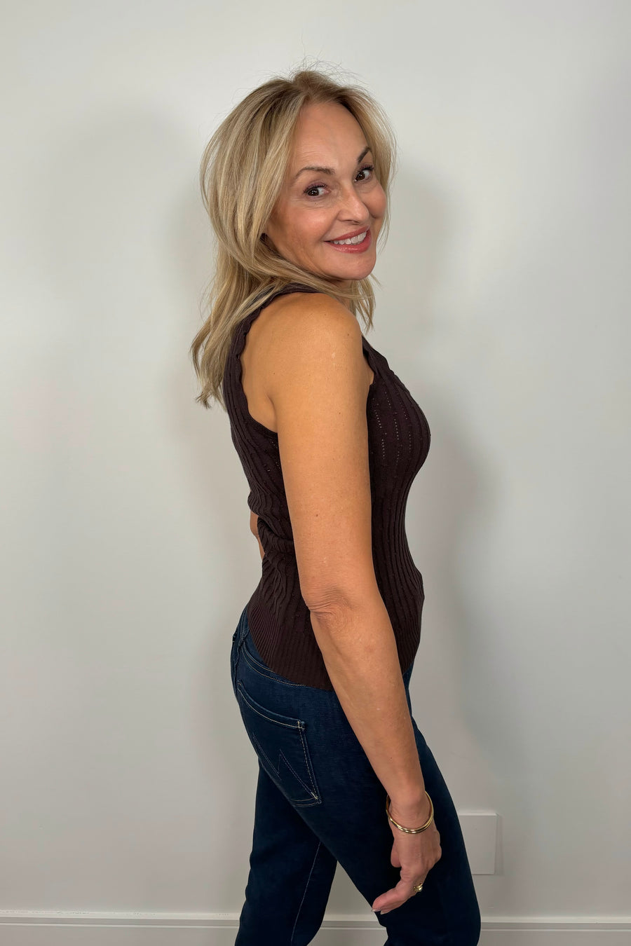 Side facing woman wearing a brown squared neck knitted tank top.