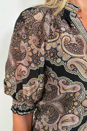 Zoom in of a woman’s right shoulder and arm wearing a cotton and silk blend black half sleeve top with a light brown pattern
