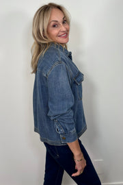 Side view of a woman wearing a relaxed blue denim long sleeve shirt