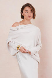 Woman wearing a white off-shoulder sweater with a plain background