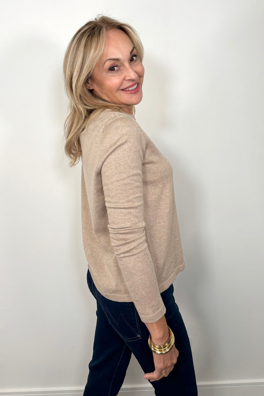 Side view of woman wearing a cashmere long sleeve beige shirt