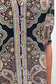 Zoom in of a woman’s torso wearing a cotton and silk blend black half sleeve top with a light brown pattern