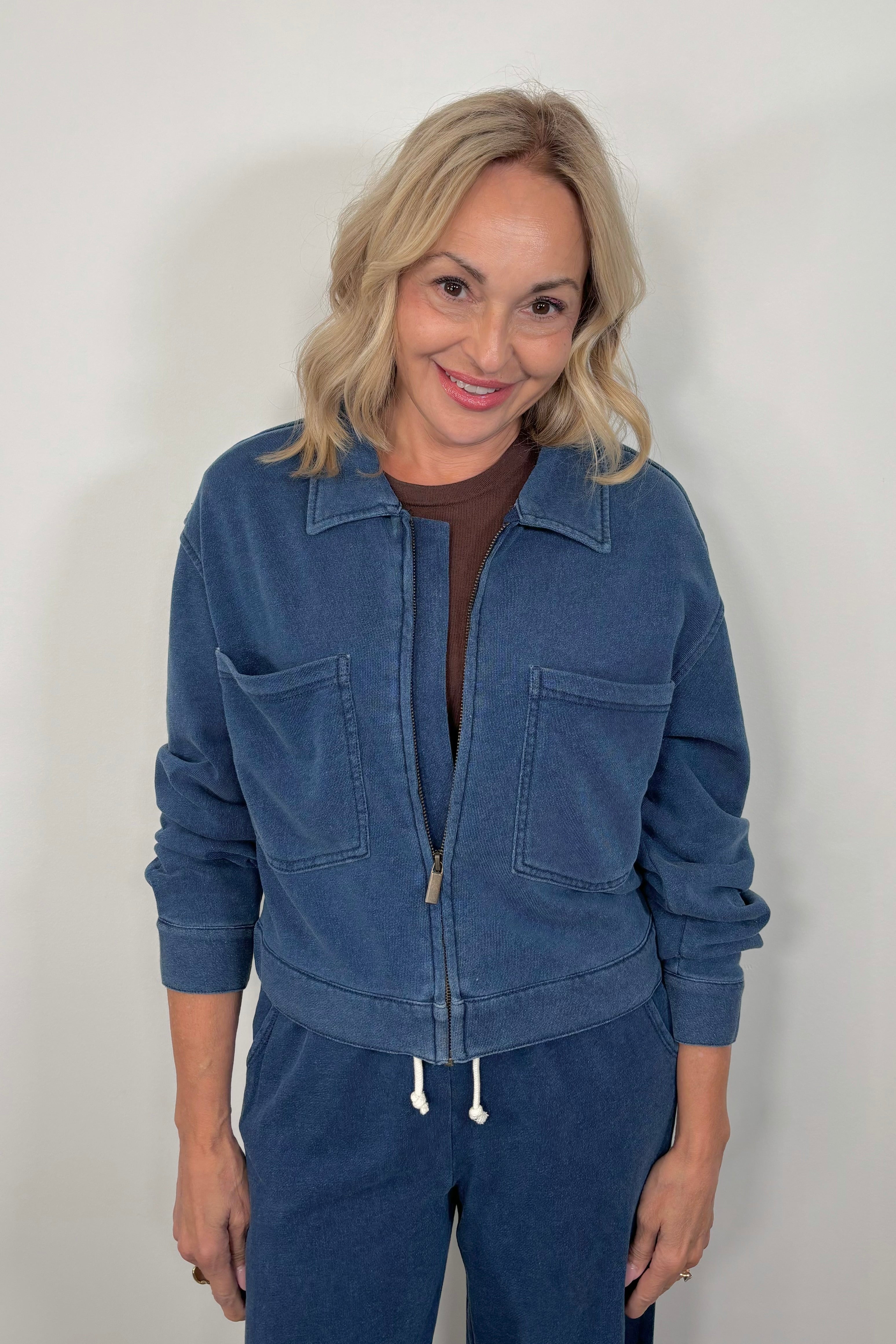 Woman wearing a blue jacket and pants against a plain background