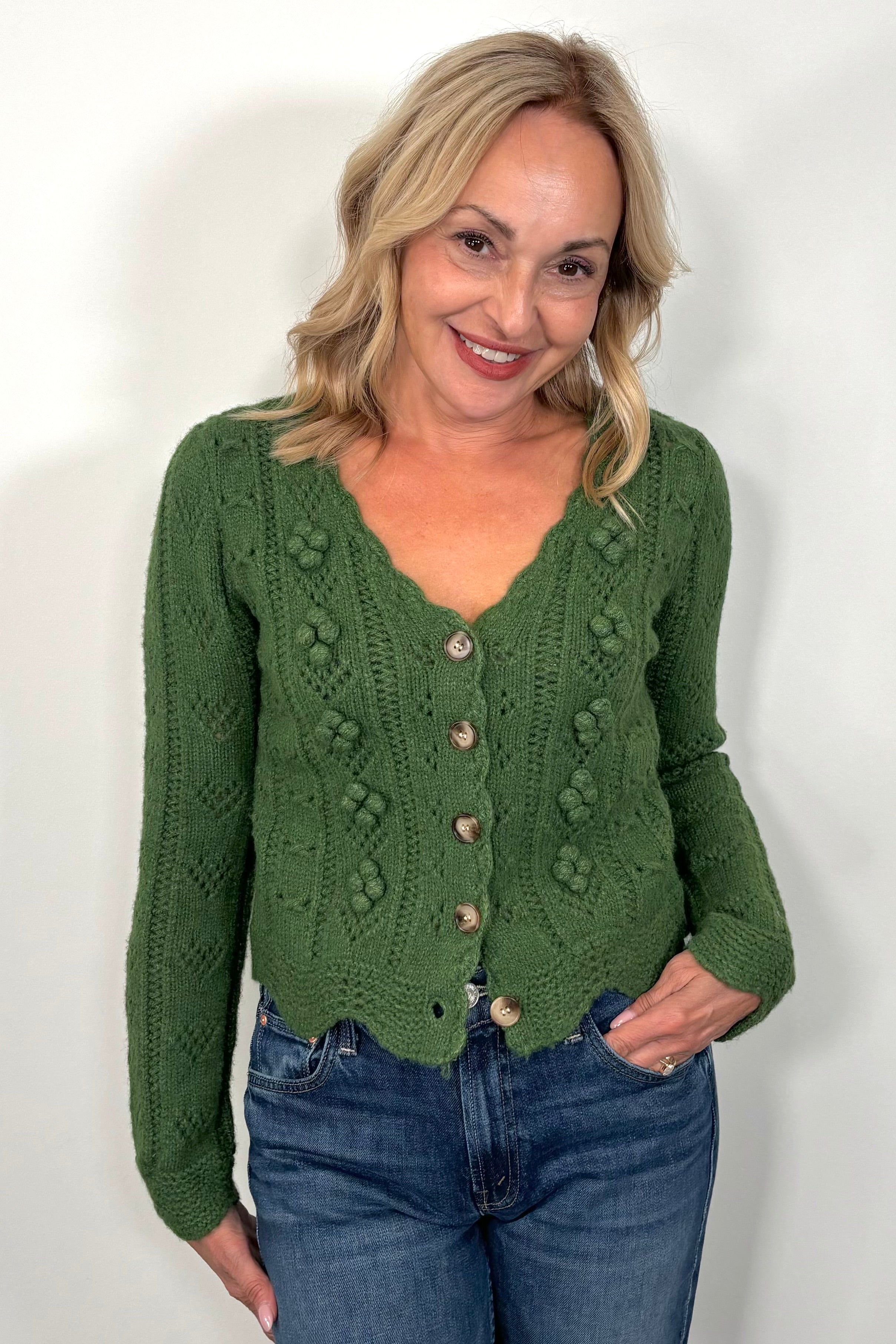 Woman wearing a green knitted cardigan against a white background