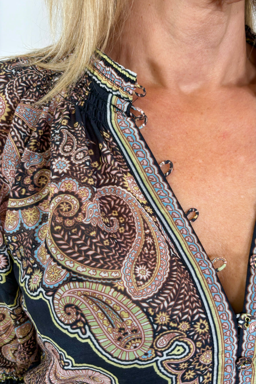 Zoom in of a woman’s right shoulder wearing a cotton and silk blend black half sleeve top with detailing in the neckline