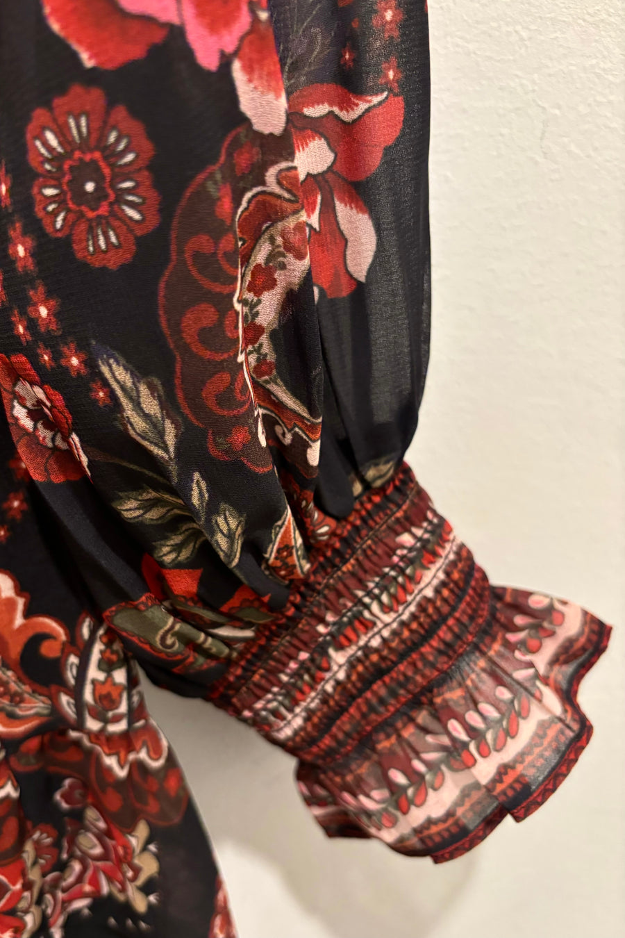 Close-up of the cuff of a short long sleeve dress with floral and paisley patterns.