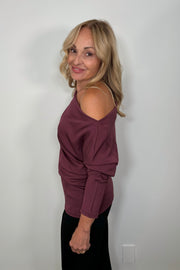 Side view of woman wearing a soft cowl neck rouched long sleeve top in merlot