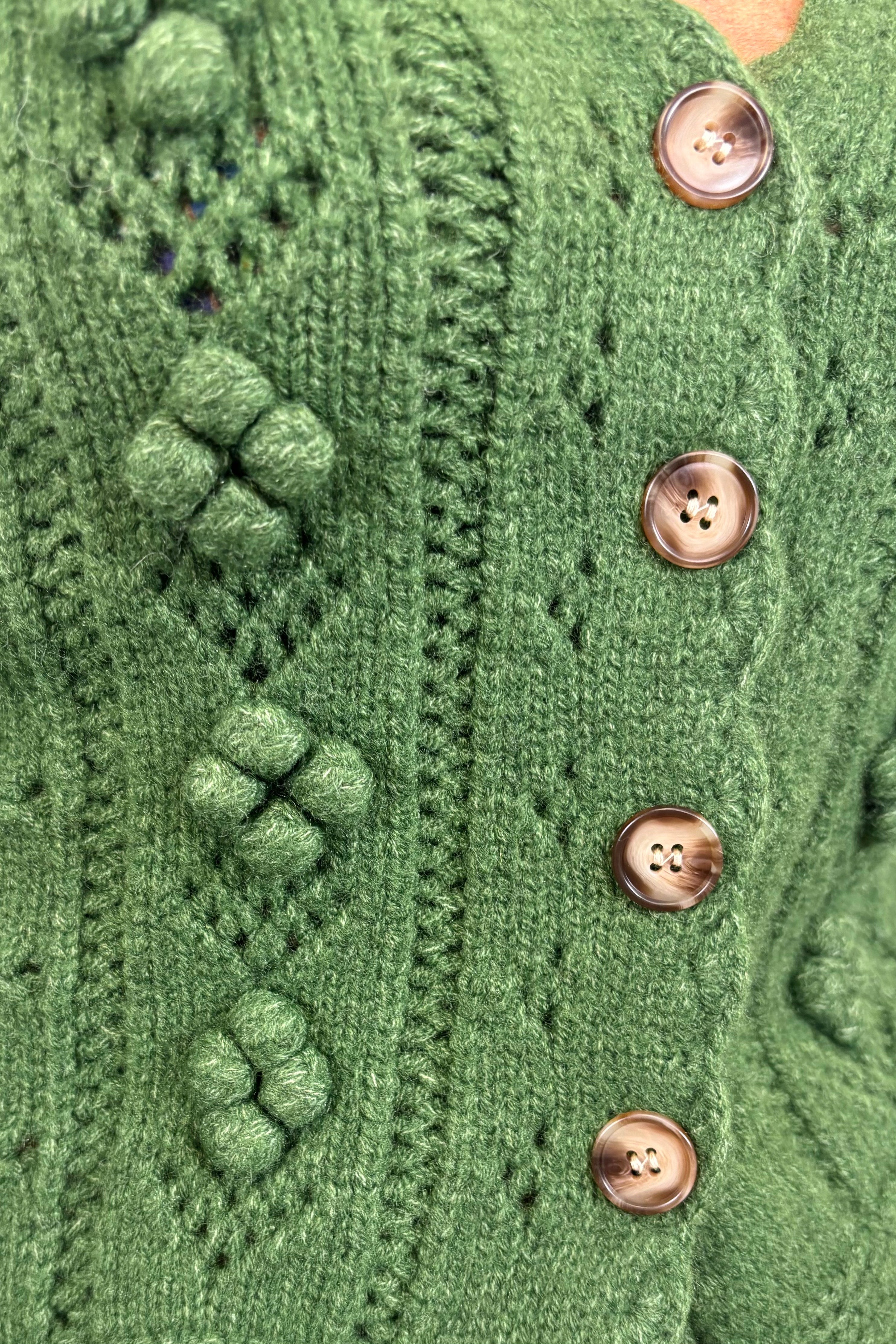 Close-up of a green knitted cardigan with button details