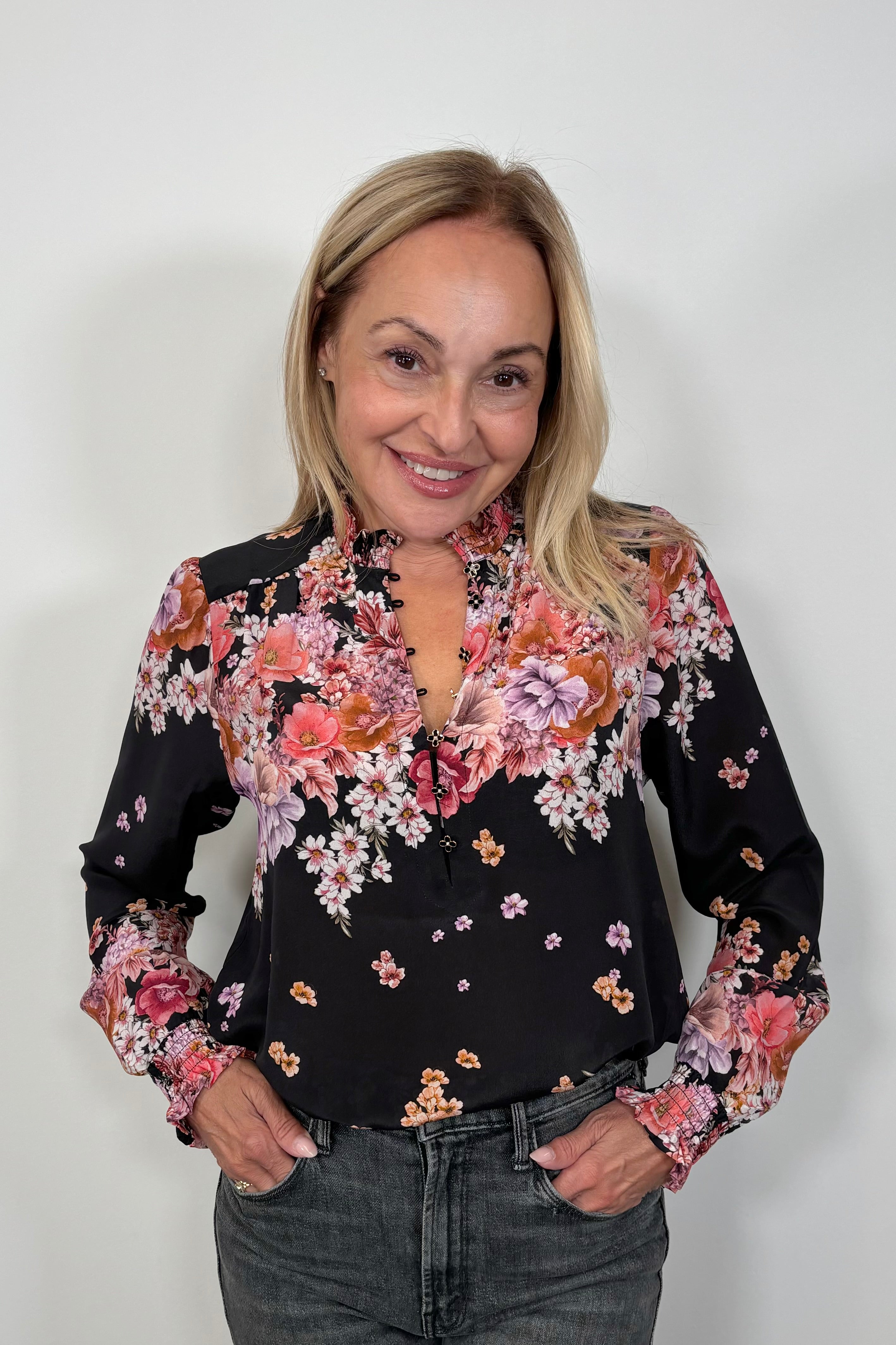 Front view of woman wearing a black long cuffed sleeve silk blouse tucked in
