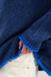 Close-up of a blue textured garment with a person wearing light-colored pants.
