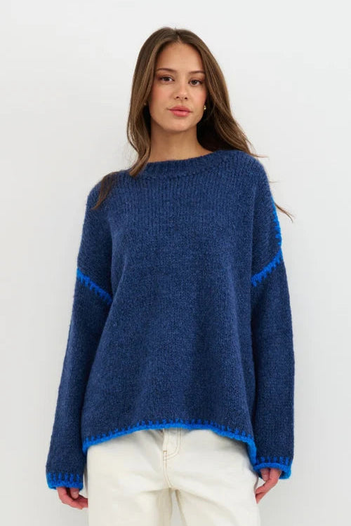 Woman wearing a blue sweater with white pants on a white background