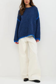Woman wearing a blue sweater and white pants on a white background