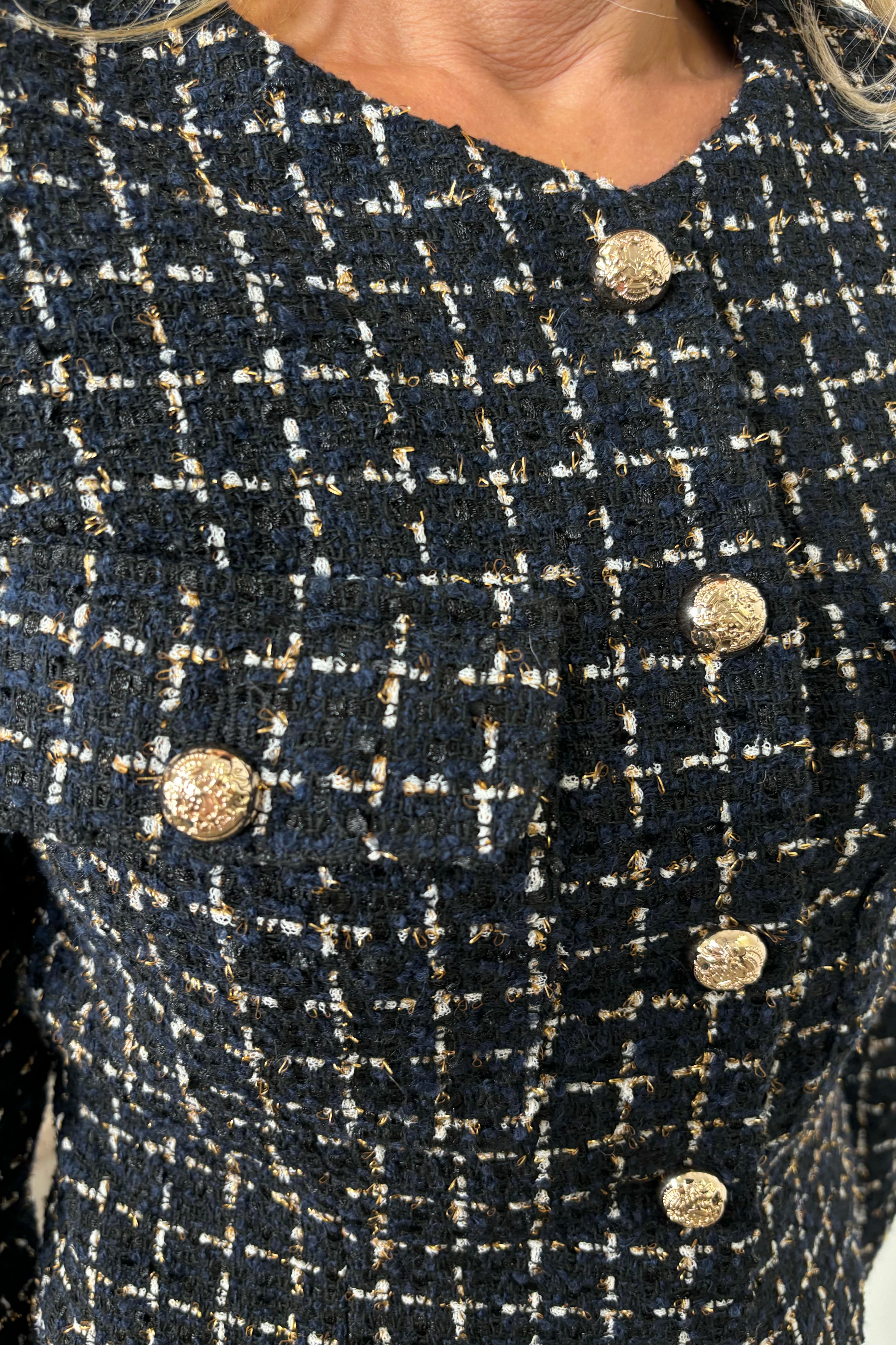Close-up Front view of a woman wearing a navy houndstood patterned blazer with gold hardware