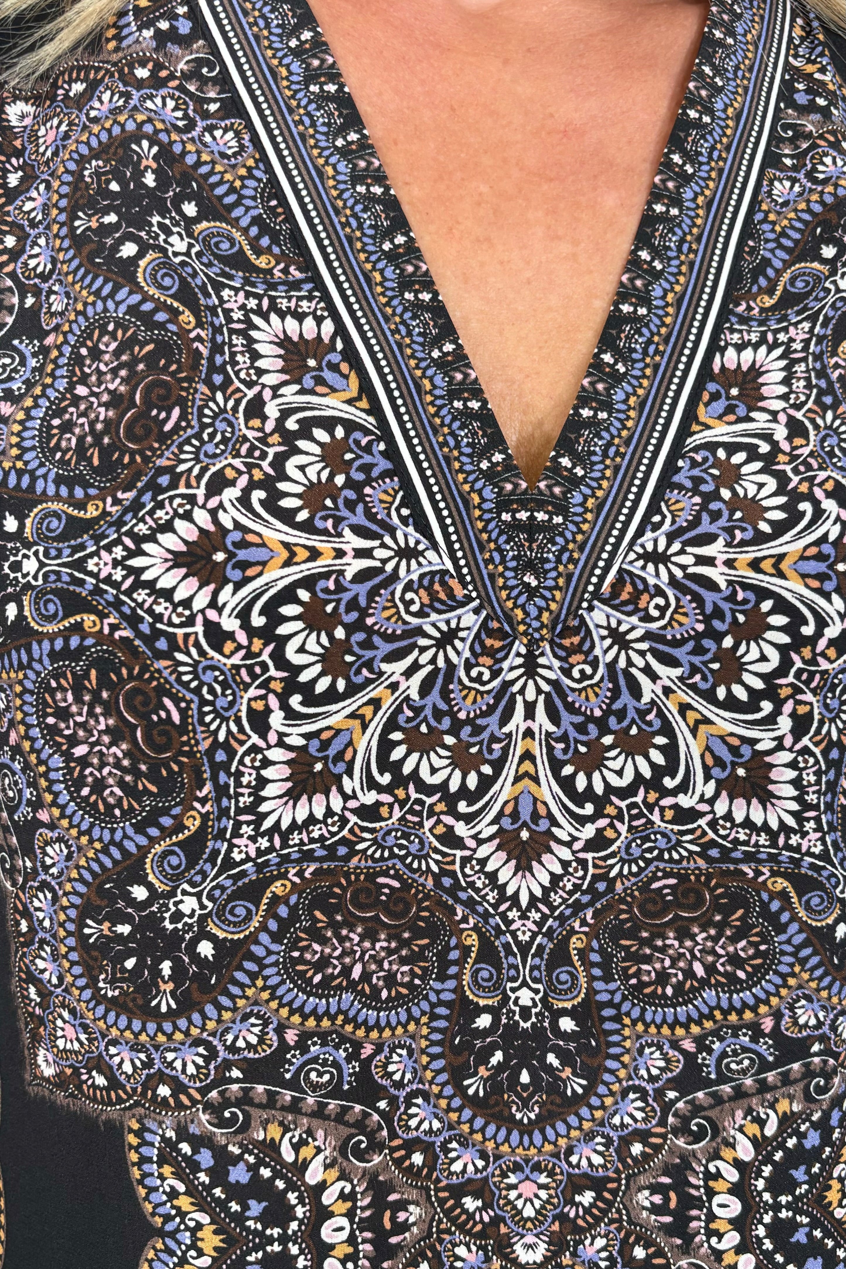 Close-up view of the neckline of a cuffed blouson sleeved patterned black blouse
