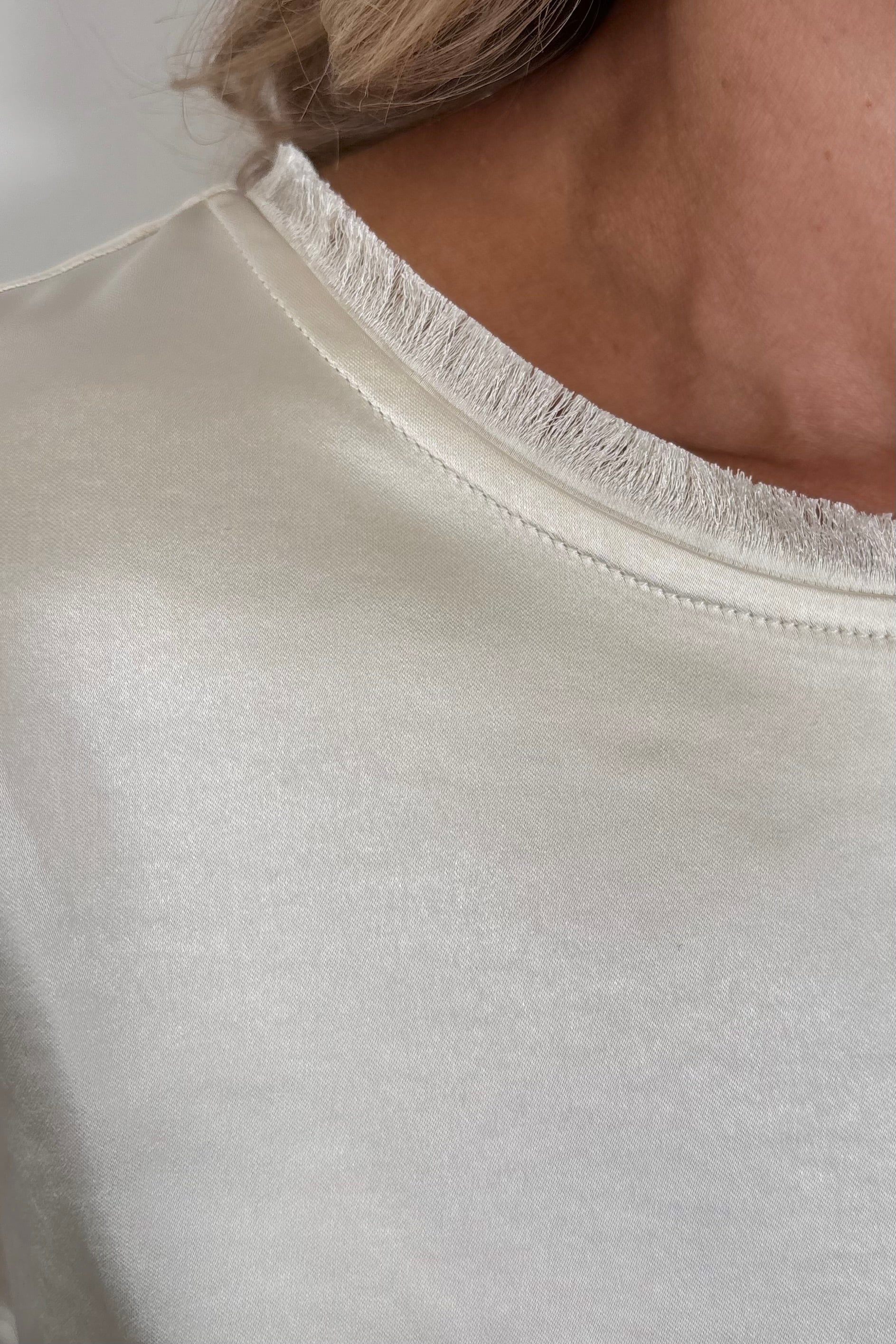 Close-up of a woman wearing a pearl satin cap sleeve tee