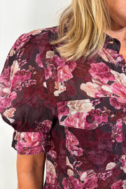 Close up of the sleeve of a see through collared button up floral shirt