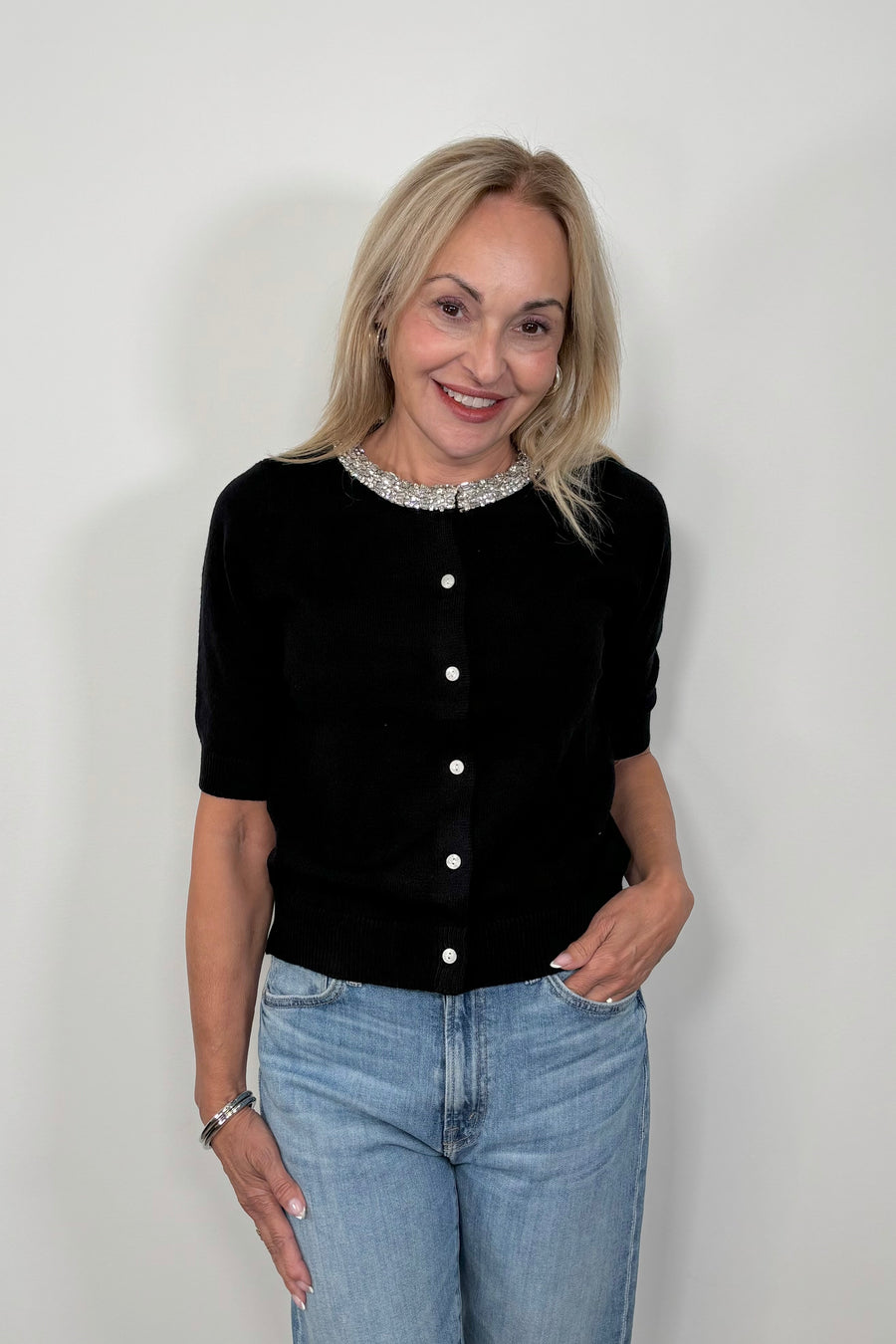 Front view of woman wearing a half sleeve black cardigan with crystal detailing