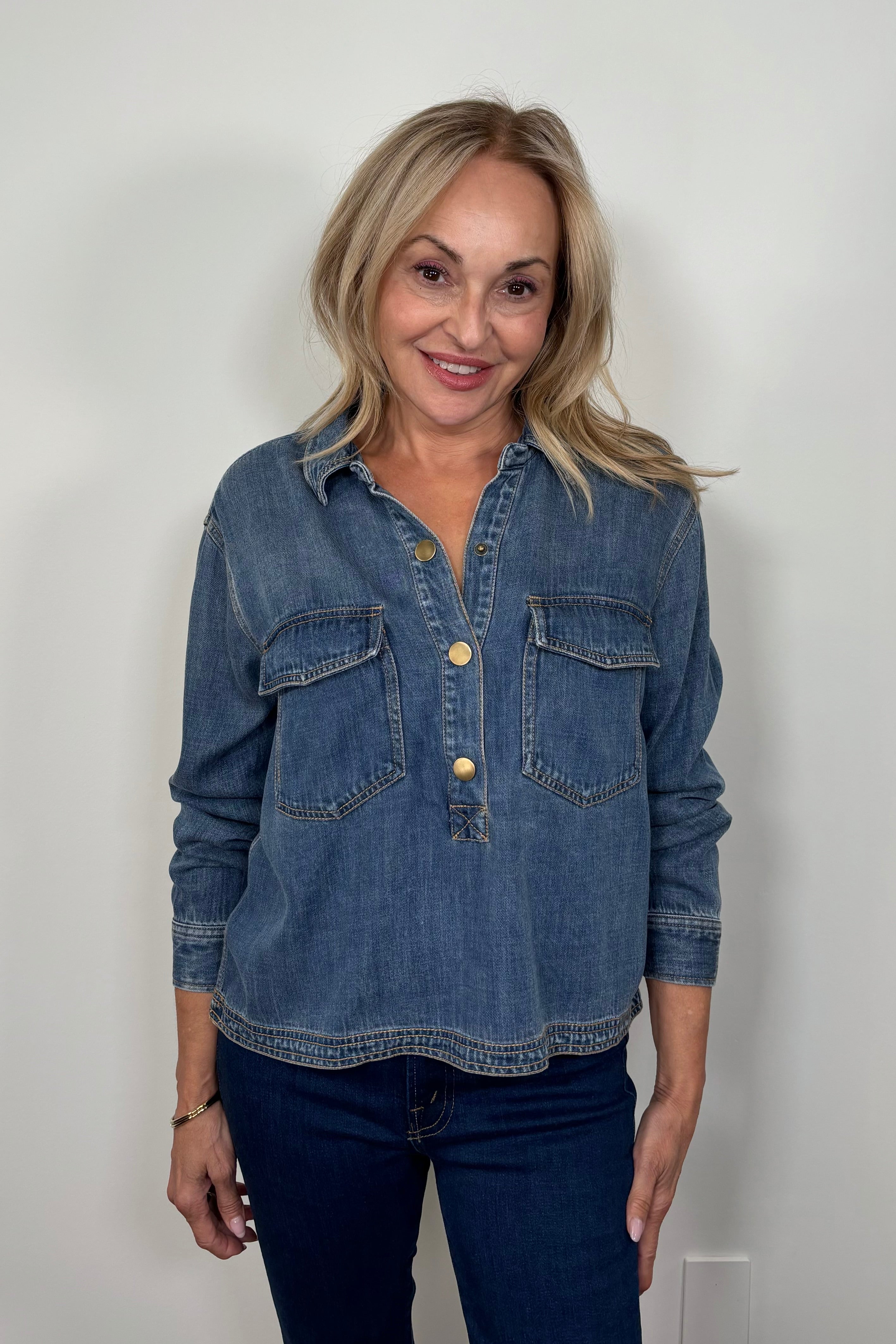 Front view of a woman wearing a relaxed blue denim long sleeve shirt