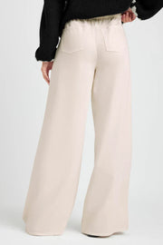 Beige wide-leg pants worn by a person on a white background