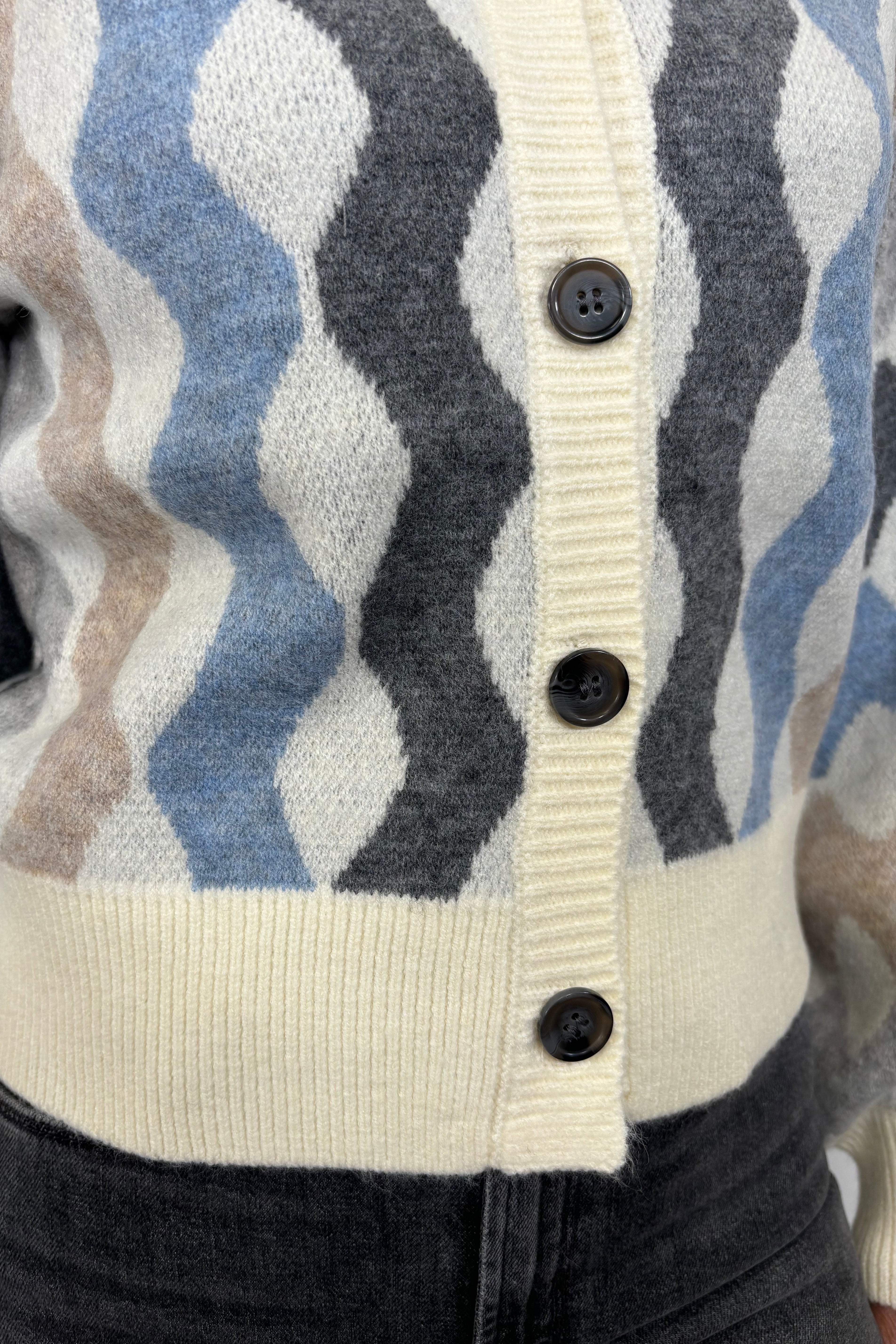 Close up view of woman wearing a cardigan with blouson sleeved and a multicoloured waive design