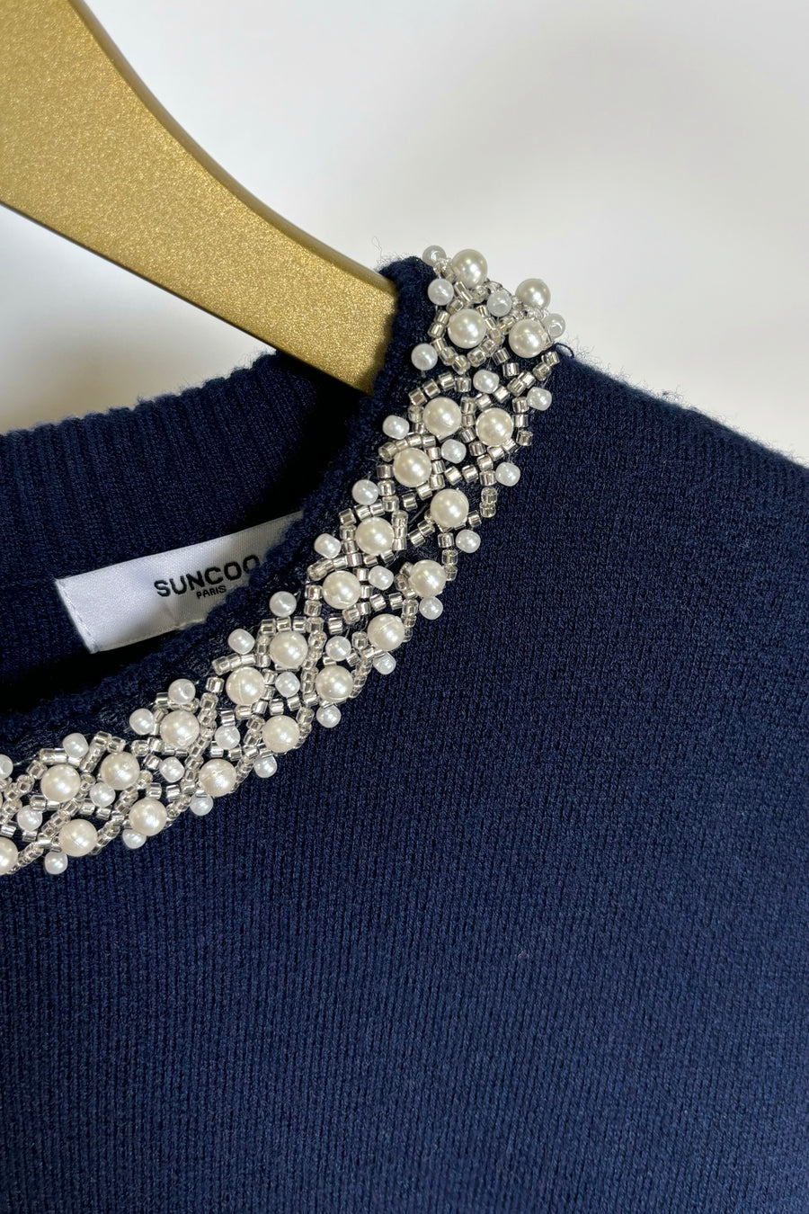 Zoom in of the neckline of a navy knitted top
