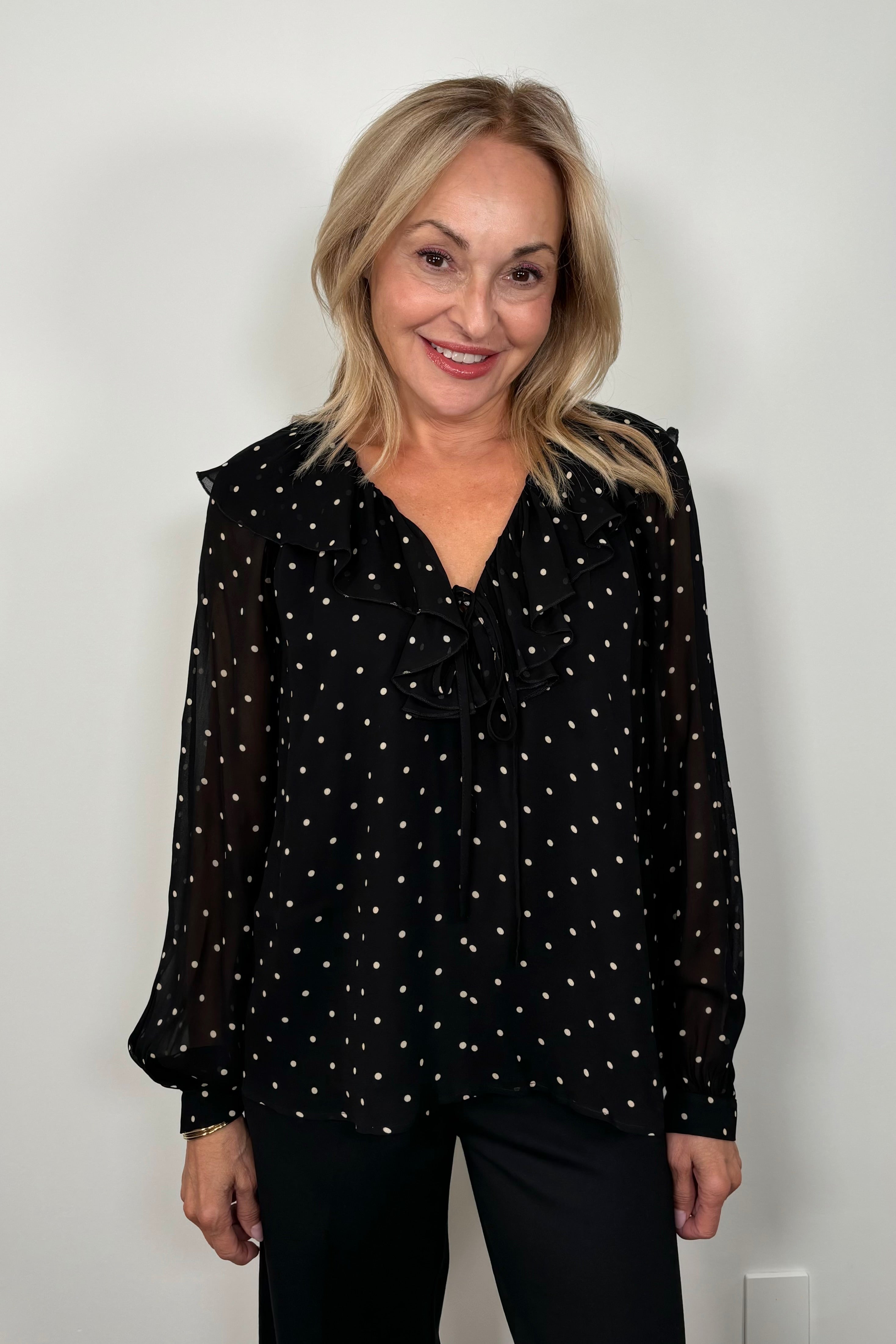 Front view of a woman wearing a sheer polka dot blouse