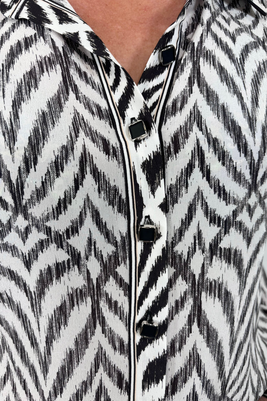 Close up view of woman wearing a Button up blouse with zig zag black stipes