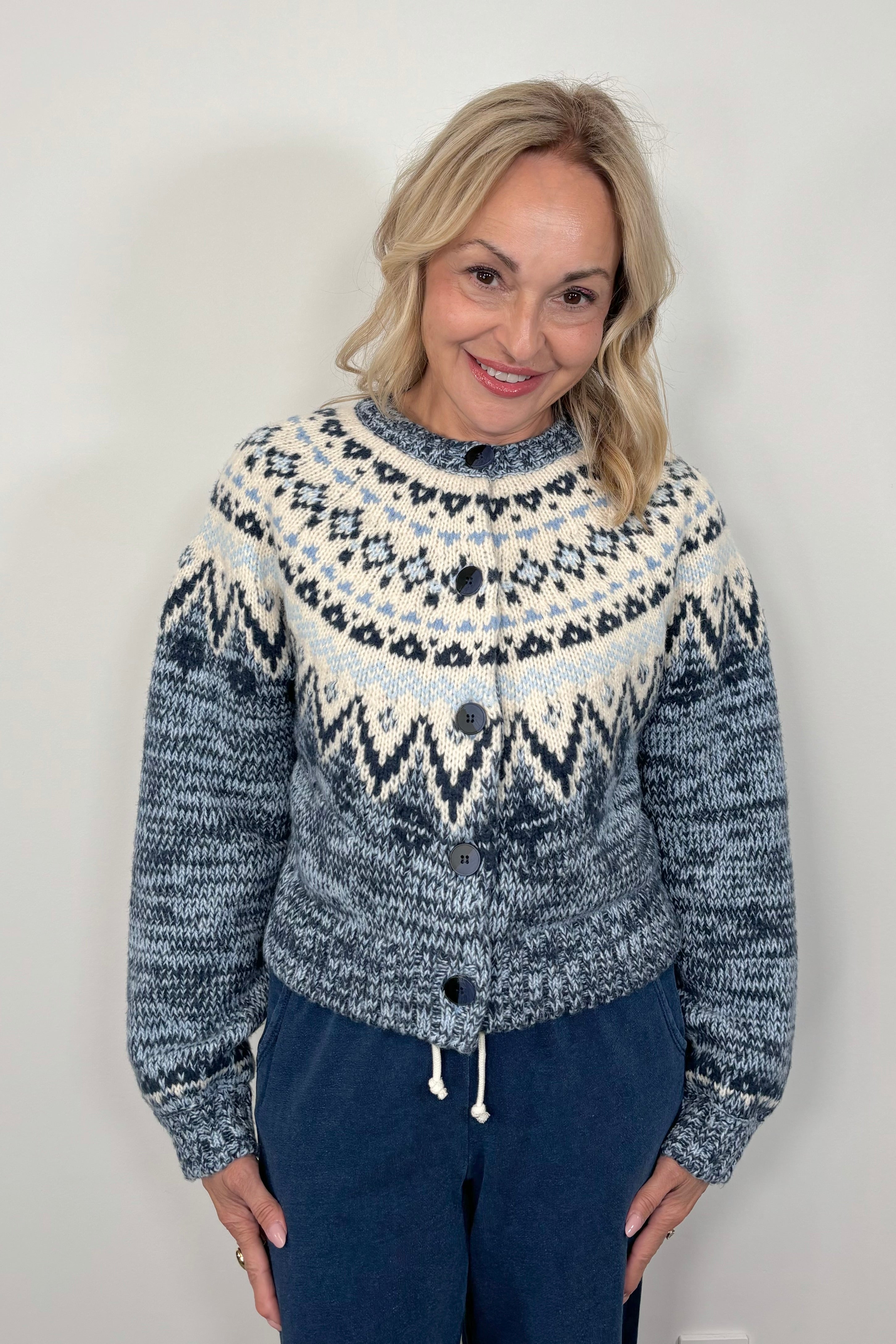 Woman wearing a blue and white patterned sweater against a plain background
