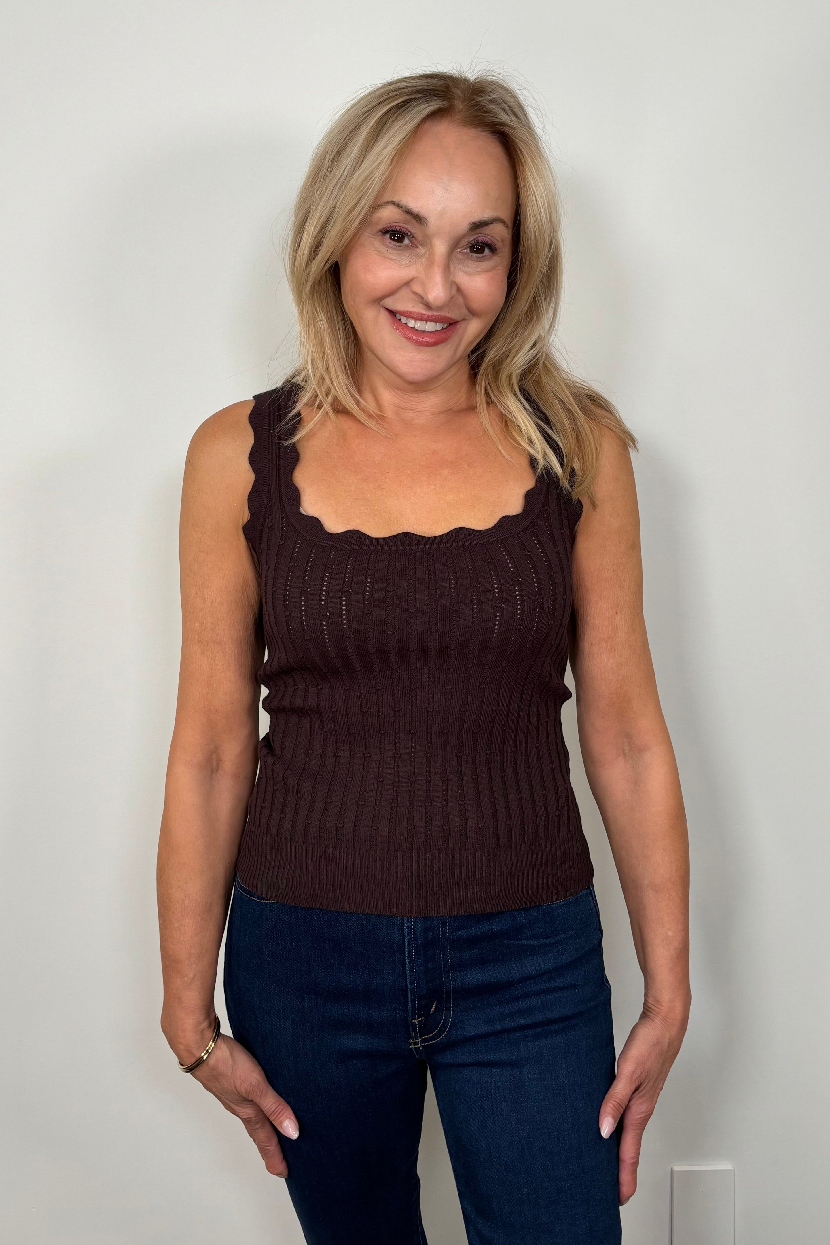 Front facing woman wearing a brown squared neck knitted tank top.