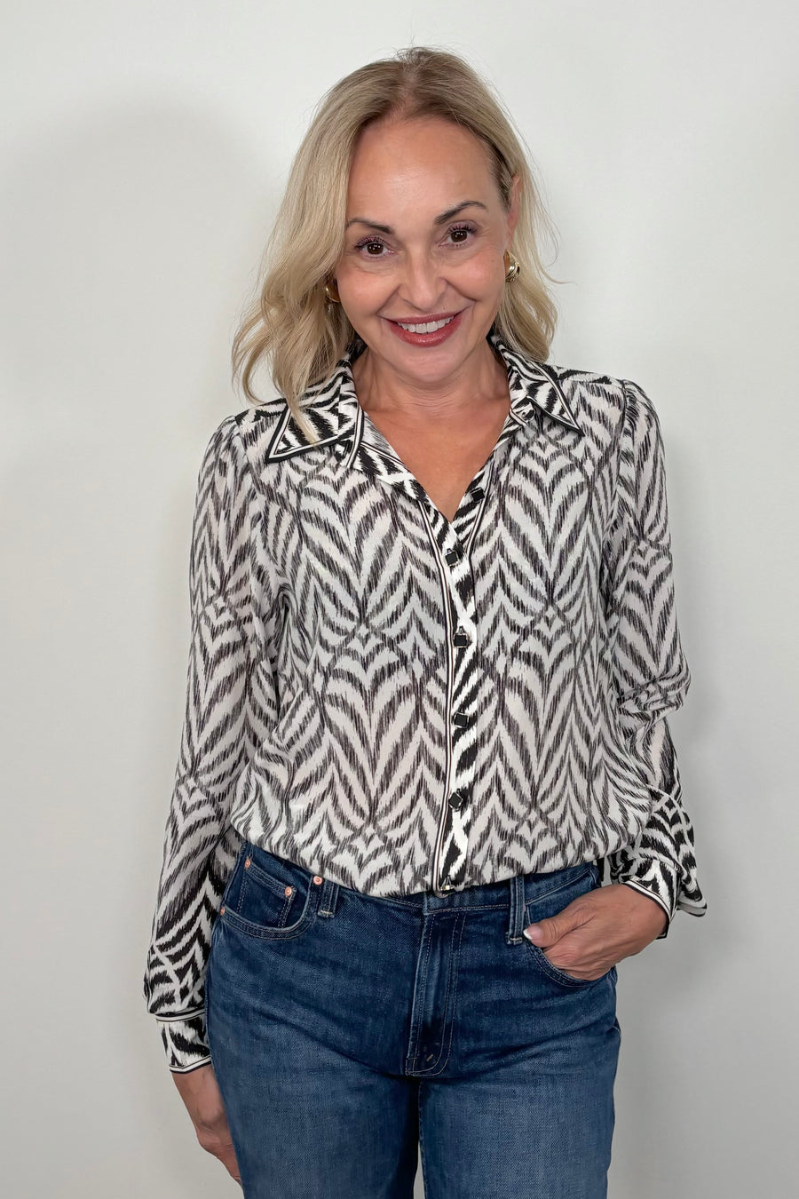 Front view of woman wearing a tucked in Button up blouse with zig zag black stipes