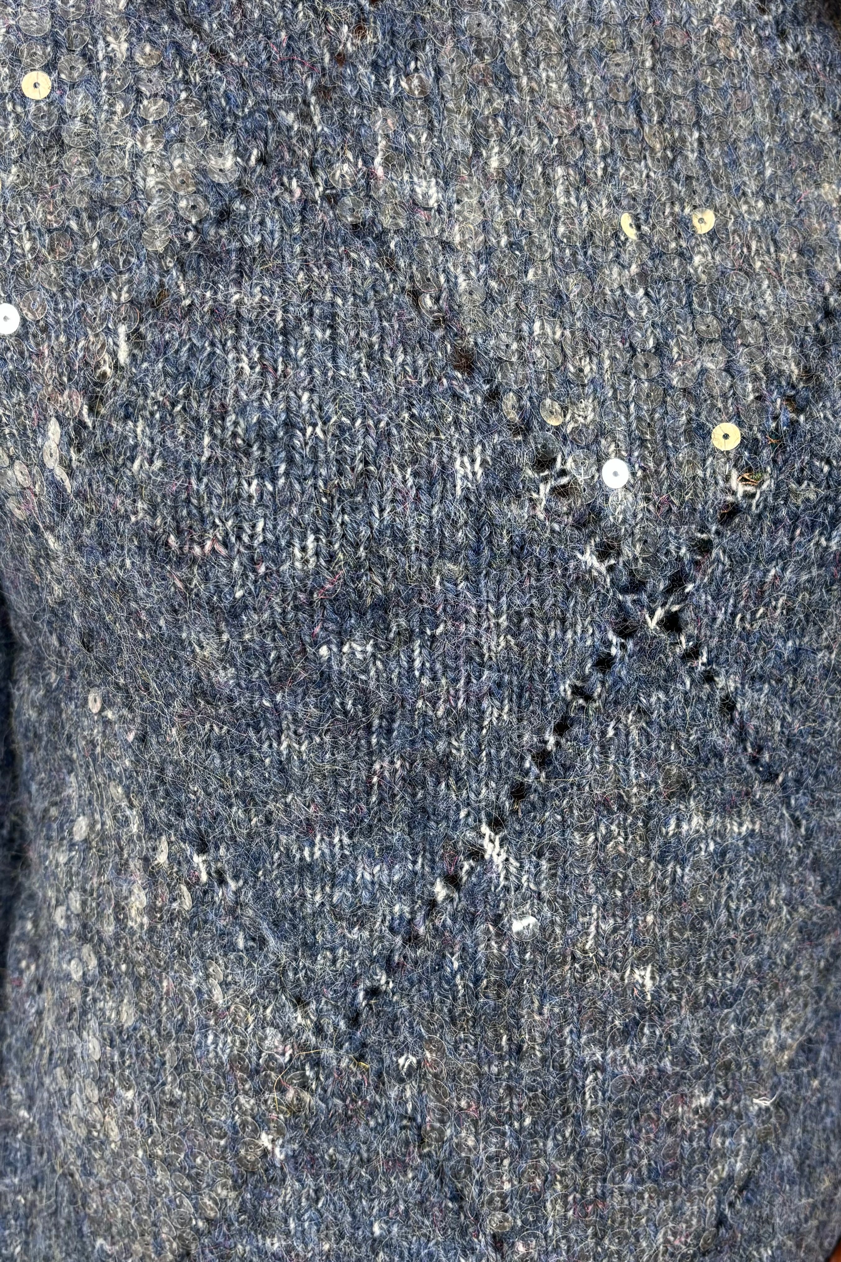 Close-up of a textured gray fabric surface with small holes and imperfections.