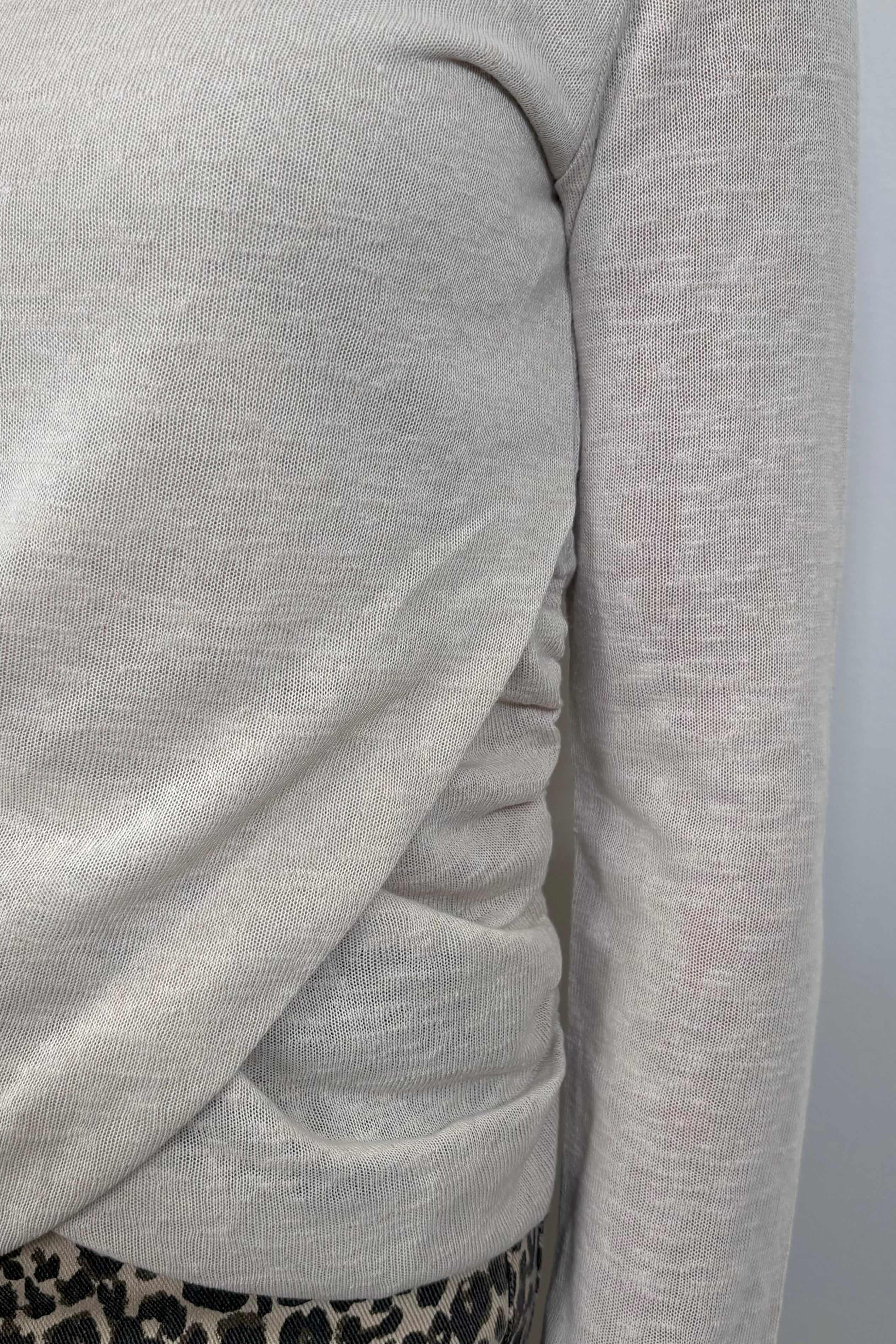 close-up of a woman wearing a light long sleeve draped beck top