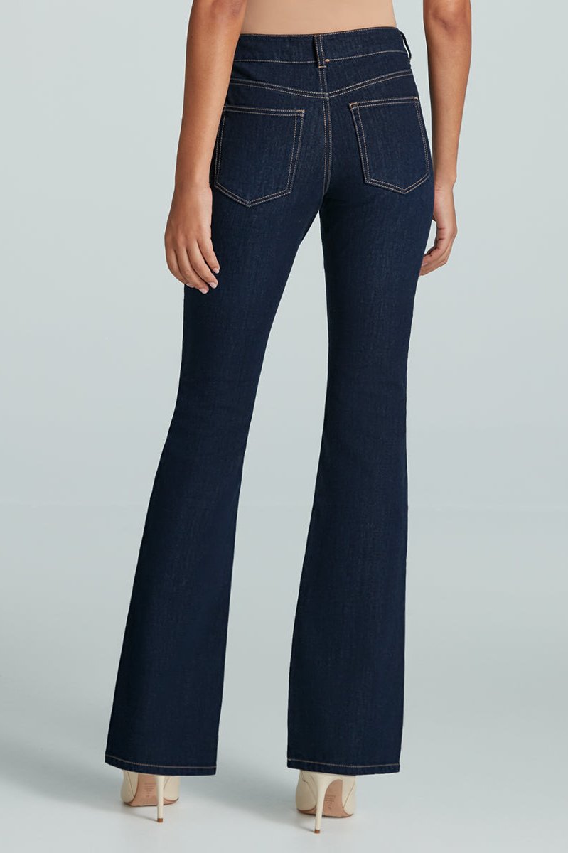 Back facing woman wearing a mid-rise flared dark wash jean