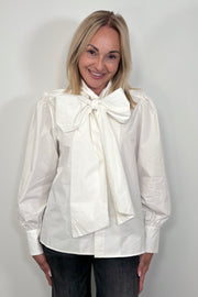Front view of woman wearing a white poplin shirt with a Bow in the neck untucked