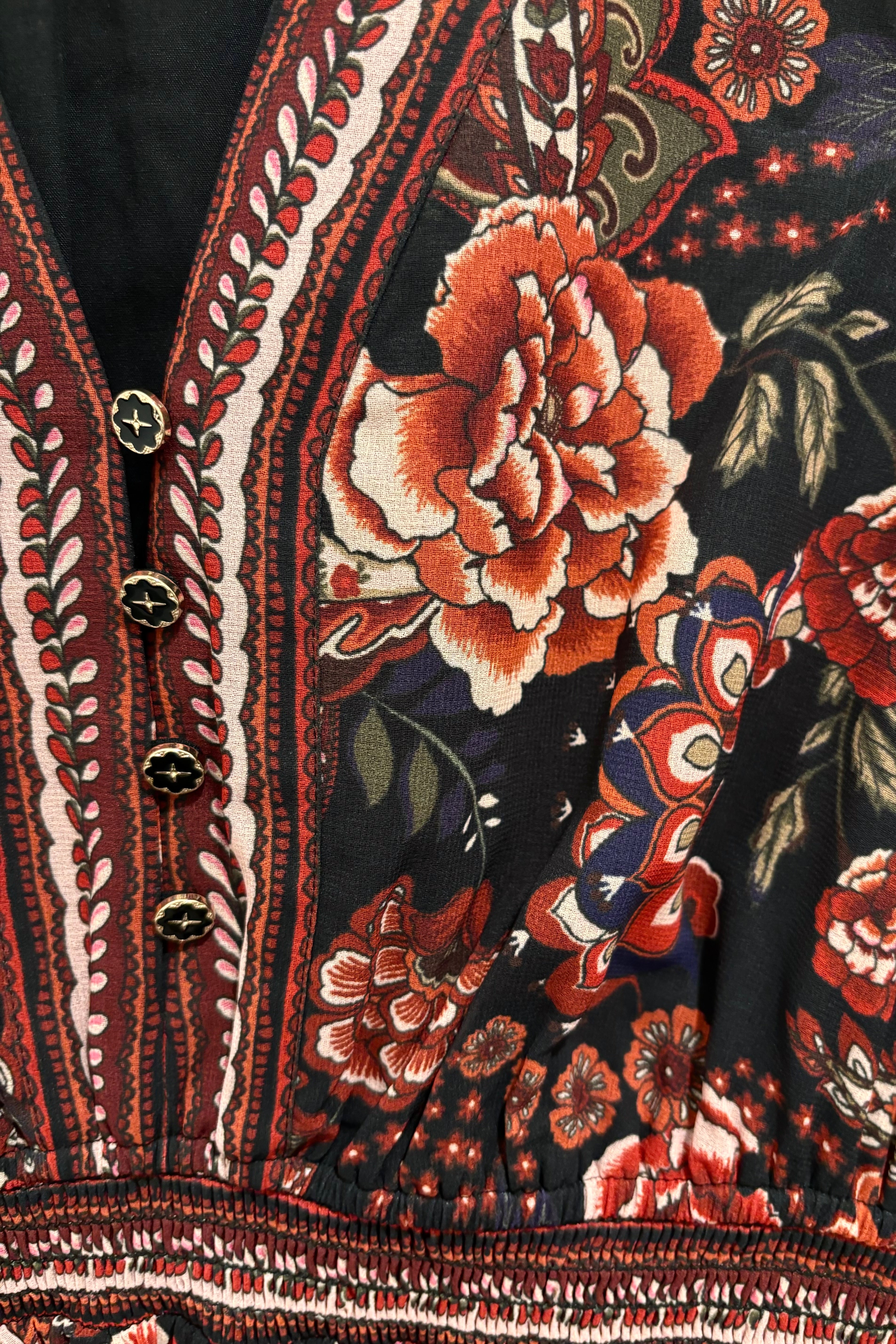 Close-up of a short long sleeve dress with floral and paisley patterns.