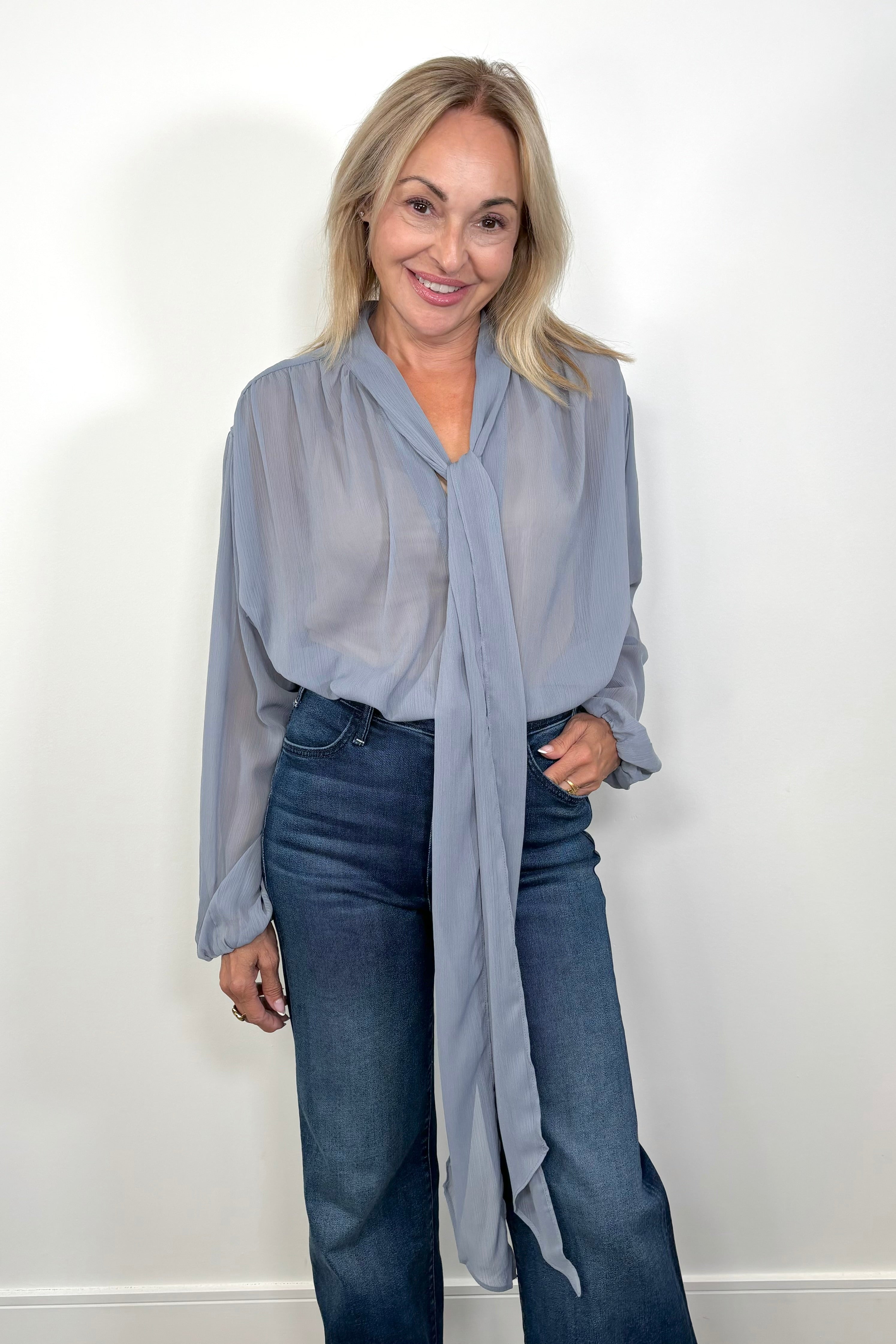 Front view of woman wearing a thin blue blouse tucked in